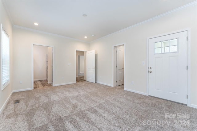 foyer entrance with plenty of natural light, crown molding, and light carpet