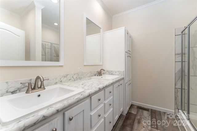 bathroom featuring hardwood / wood-style flooring, ornamental molding, double vanity, and an enclosed shower