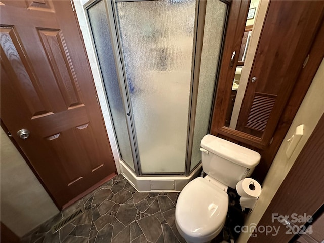 bathroom featuring walk in shower, toilet, and tile patterned floors