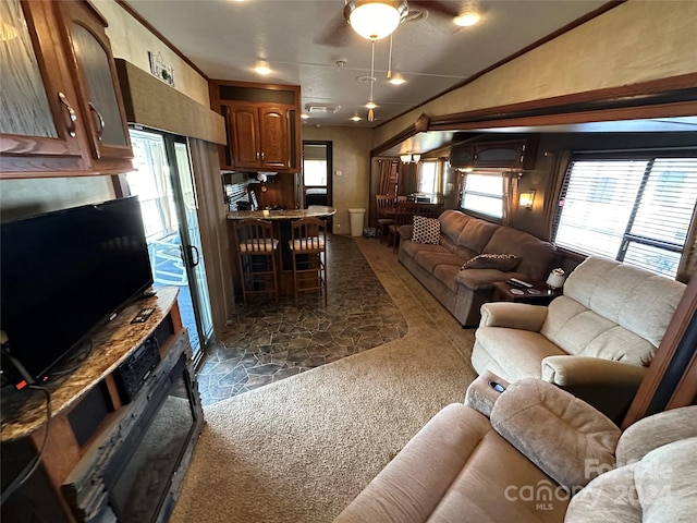 carpeted living room with ceiling fan, crown molding, vaulted ceiling, and a wealth of natural light