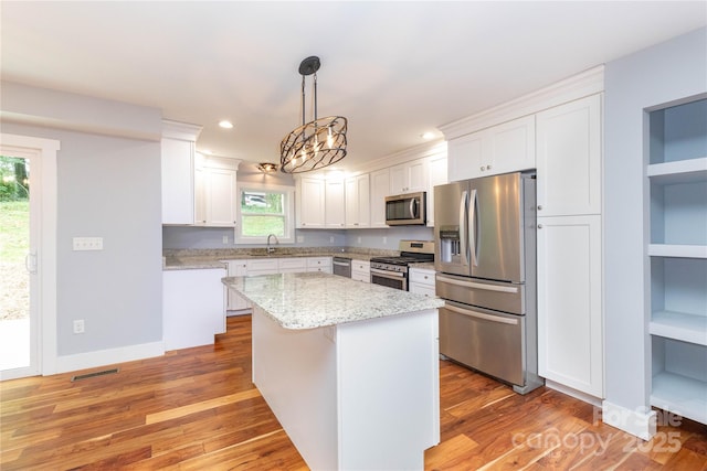 kitchen with pendant lighting, a center island, built in features, stainless steel appliances, and white cabinets