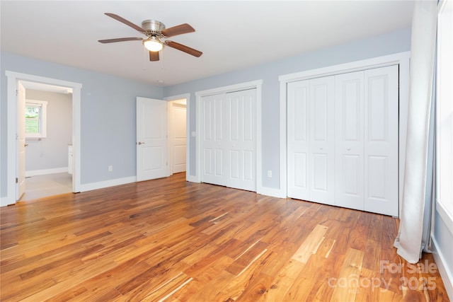 unfurnished bedroom with ceiling fan, multiple closets, connected bathroom, and light hardwood / wood-style floors