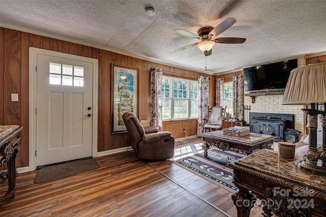 living area featuring crown molding, wood walls, and wood finished floors