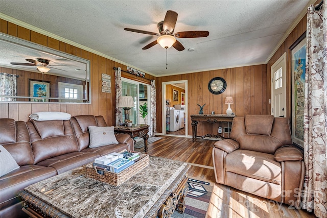 living room with a textured ceiling, wood finished floors, a ceiling fan, washer and dryer, and crown molding