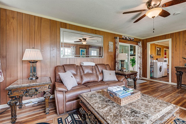 living area with ornamental molding, ceiling fan, a textured ceiling, wood finished floors, and independent washer and dryer