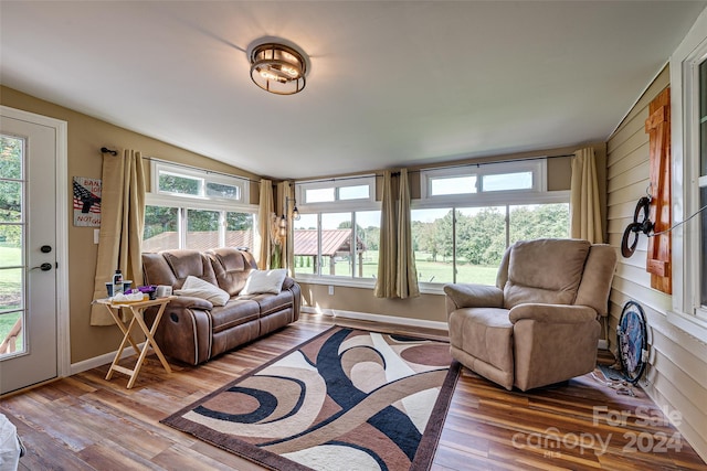 living room with a healthy amount of sunlight, vaulted ceiling, and wood finished floors