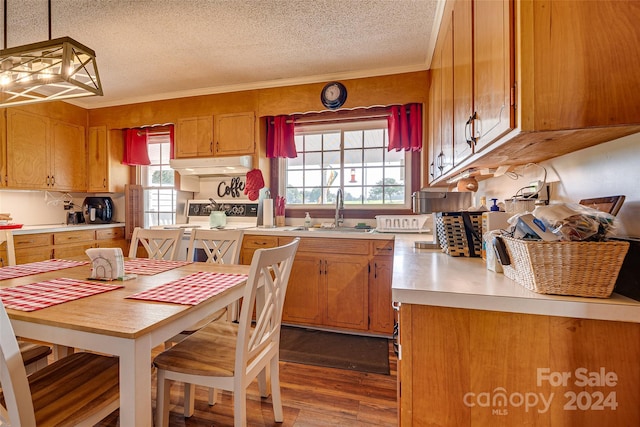 kitchen with brown cabinetry, light countertops, a sink, and decorative light fixtures