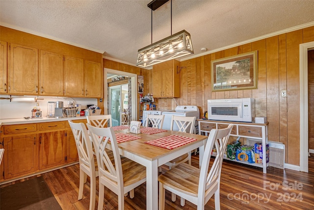 dining space with washer / dryer, dark wood finished floors, a textured ceiling, crown molding, and wood walls