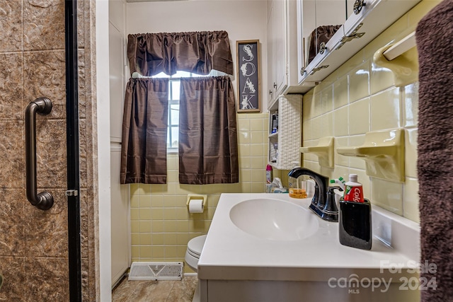 full bath with toilet, visible vents, tile walls, and vanity