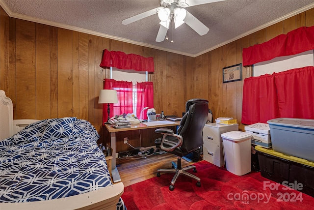 bedroom featuring wooden walls, ornamental molding, a textured ceiling, and wood finished floors