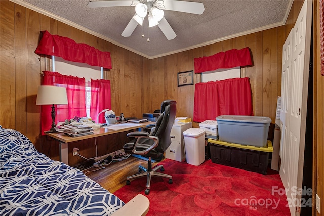 bedroom with a textured ceiling, ornamental molding, wood walls, and a ceiling fan