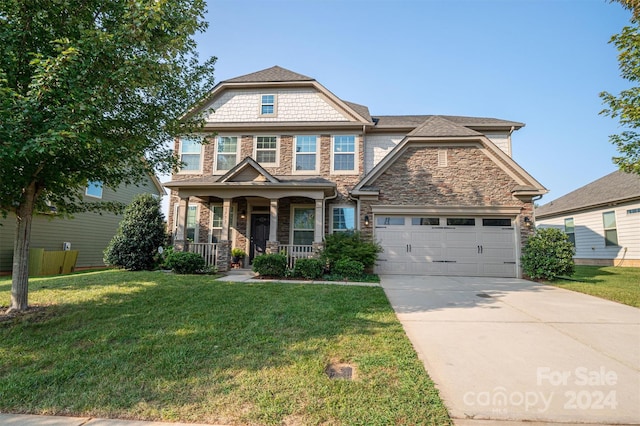 view of front of house with a garage, a front lawn, and covered porch