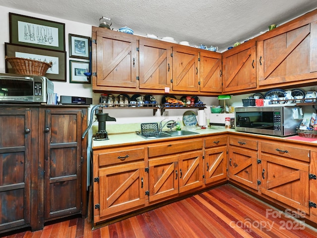 kitchen with dark hardwood / wood-style floors, sink, and a textured ceiling