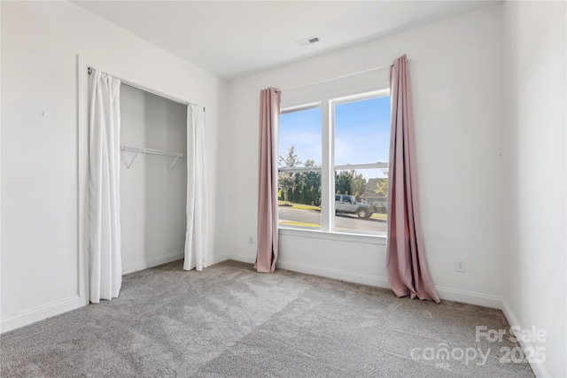 unfurnished bedroom with baseboards, visible vents, a closet, and light colored carpet