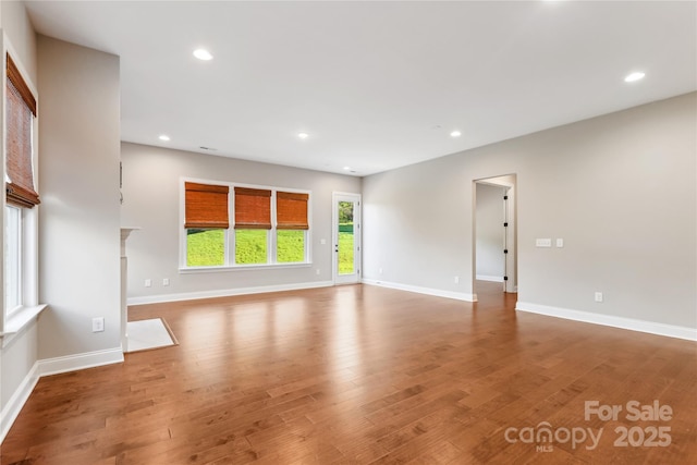 unfurnished living room with baseboards, wood finished floors, and recessed lighting