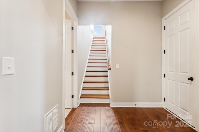 hall featuring dark wood-style floors, stairway, visible vents, and baseboards