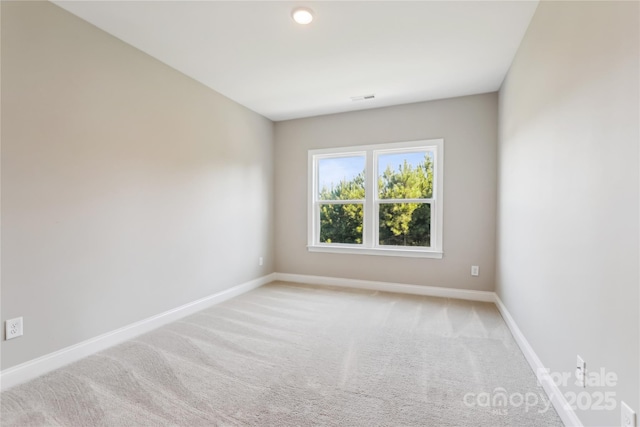 empty room with light colored carpet, visible vents, and baseboards