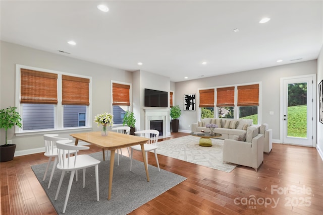 living room featuring a fireplace with flush hearth, dark wood-type flooring, and recessed lighting