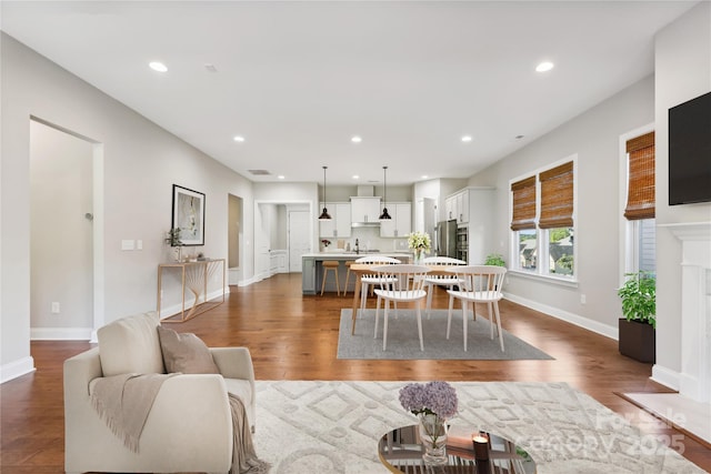 living room with dark wood-style floors, baseboards, a high end fireplace, and recessed lighting