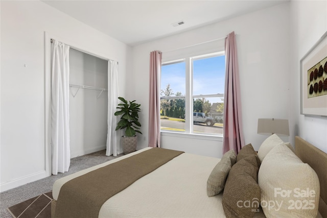 carpeted bedroom featuring baseboards, visible vents, and a closet