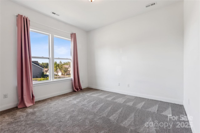 carpeted spare room featuring visible vents and baseboards