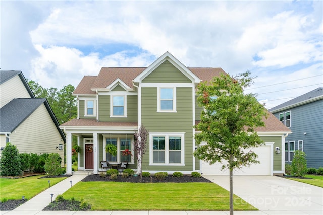 view of front of property featuring a garage, a front yard, and covered porch