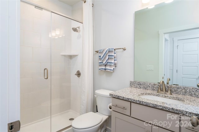 bathroom with vanity, a shower with door, and toilet