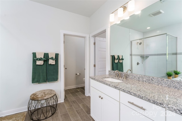 bathroom featuring vanity, walk in shower, and toilet