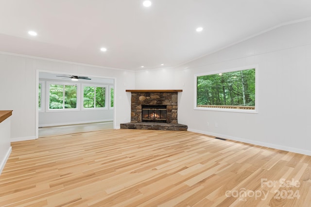 unfurnished living room with vaulted ceiling, crown molding, light wood-type flooring, a fireplace, and ceiling fan