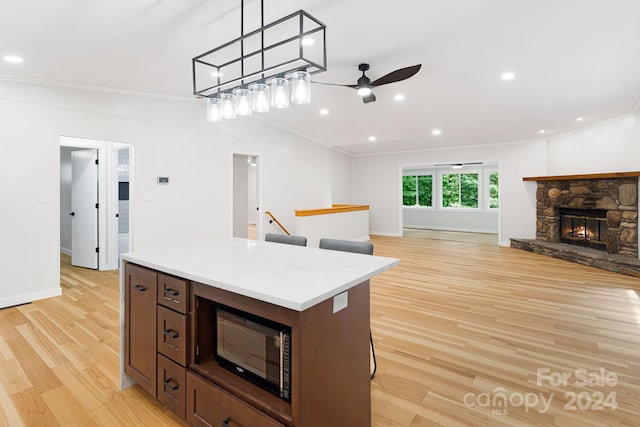 kitchen featuring ornamental molding, stainless steel microwave, light wood-type flooring, ceiling fan, and hanging light fixtures