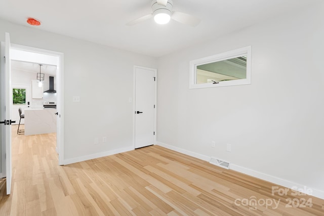 empty room with ceiling fan and light hardwood / wood-style flooring