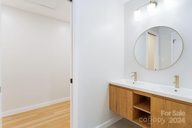 bathroom with double vanity and wood-type flooring