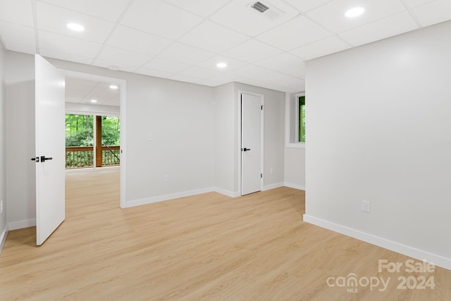 spare room with plenty of natural light, light hardwood / wood-style flooring, and a paneled ceiling