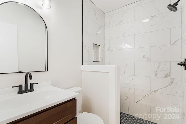 bathroom featuring tiled shower, toilet, and vanity