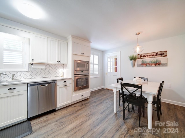 kitchen featuring pendant lighting, hardwood / wood-style floors, stainless steel appliances, and sink