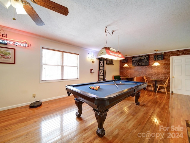 game room featuring a textured ceiling, brick wall, pool table, light hardwood / wood-style flooring, and ceiling fan