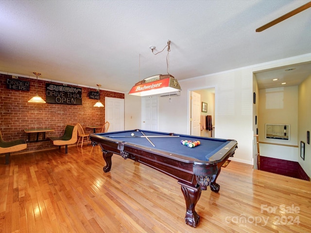 rec room featuring billiards, light hardwood / wood-style flooring, brick wall, and a textured ceiling