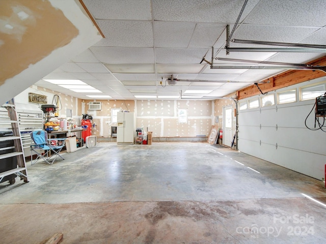 garage with white refrigerator with ice dispenser and an AC wall unit