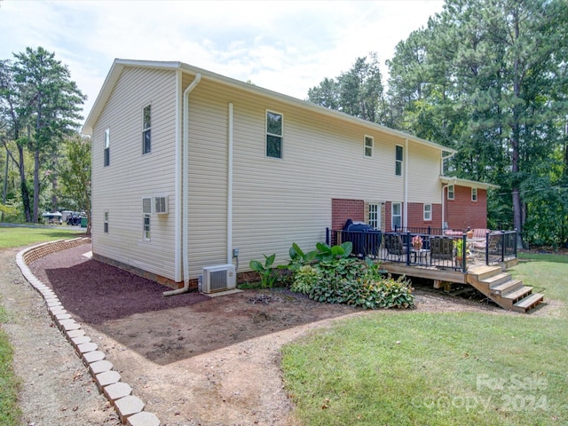 back of house featuring a wooden deck, a lawn, and ac unit