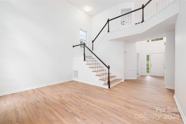 entryway featuring a wealth of natural light, light hardwood / wood-style floors, and a high ceiling