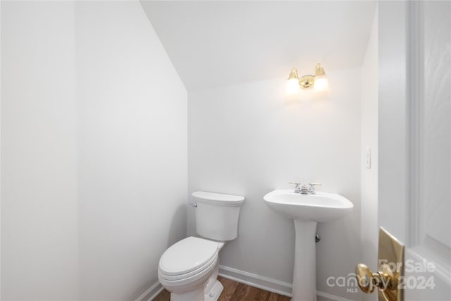 bathroom with hardwood / wood-style floors, toilet, and lofted ceiling