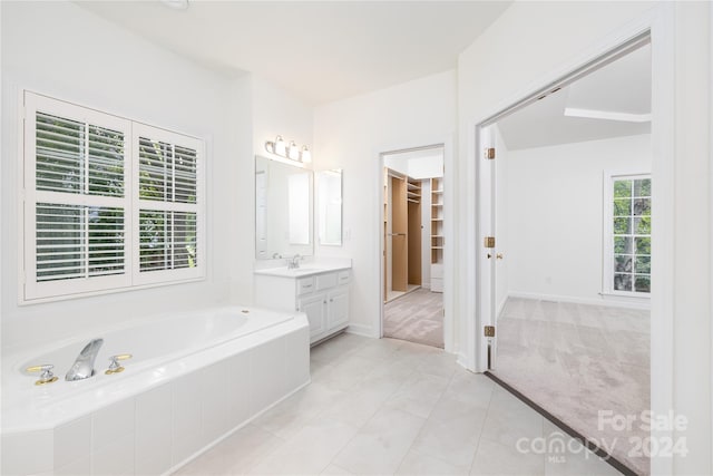 bathroom with tile patterned flooring, vanity, and a relaxing tiled tub