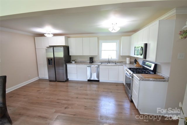 kitchen with sink, ornamental molding, light wood-type flooring, stainless steel appliances, and white cabinets