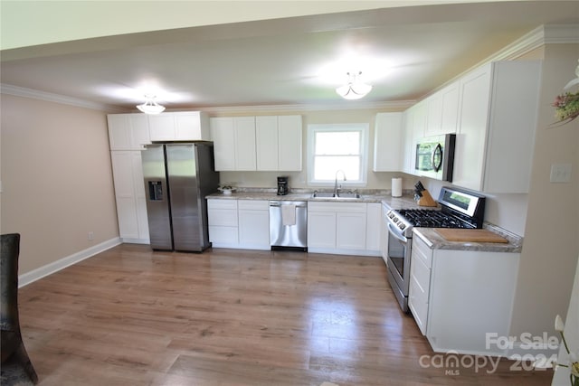 kitchen with light wood-type flooring, ornamental molding, a sink, stainless steel appliances, and white cabinets