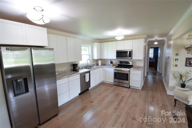 kitchen with ornamental molding, appliances with stainless steel finishes, light stone counters, light hardwood / wood-style floors, and white cabinetry