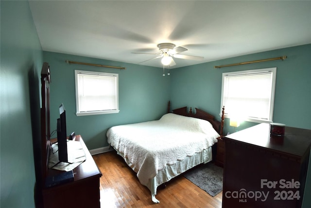 bedroom with ceiling fan, hardwood / wood-style flooring, and multiple windows