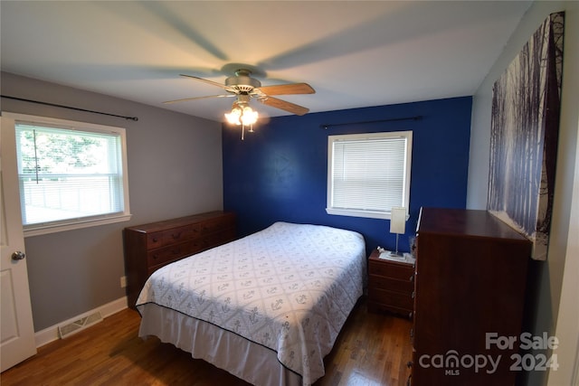 bedroom with ceiling fan, wood finished floors, visible vents, and baseboards