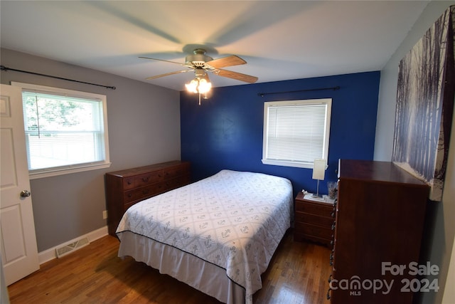bedroom featuring visible vents, a ceiling fan, baseboards, and wood finished floors