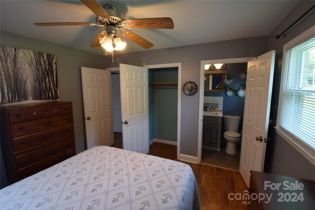 bedroom with connected bathroom, dark wood-type flooring, ceiling fan, a closet, and a sink
