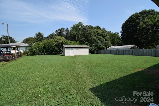 view of yard with a storage shed, an outdoor structure, and fence
